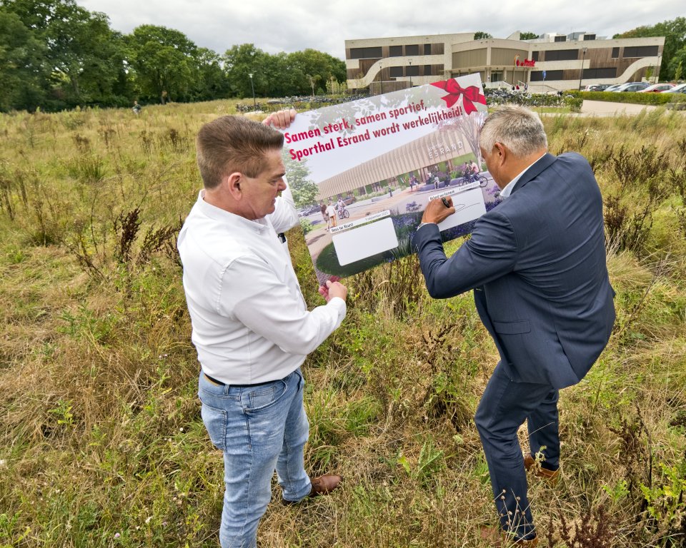 Wethouder Hans ter Keurst en directeur van Pellikaan bv Richard van Emmerik ondertekenen een bord met de tekst ‘Samen sterk, samen sportief, sporthal Esrand wordt werkelijkheid!’ op het bouwterrein.