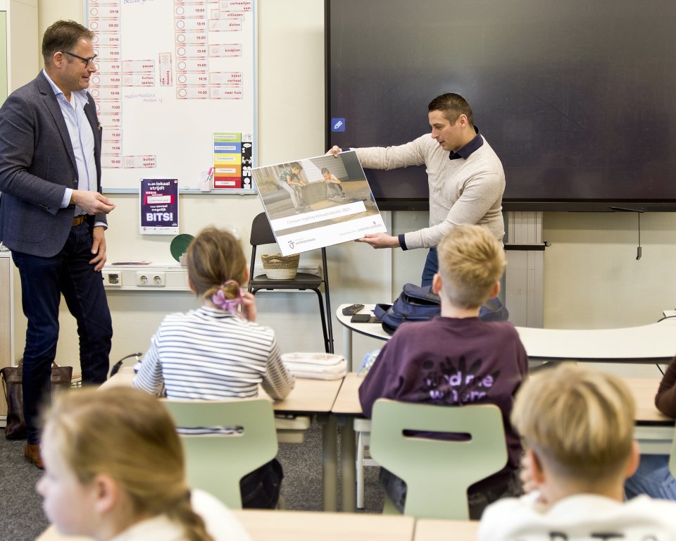 Wethouder ten Brinke ontvangt een klimaatsubsidiecheque in het klaslokaal van groep 6 van de Sjaloomschool