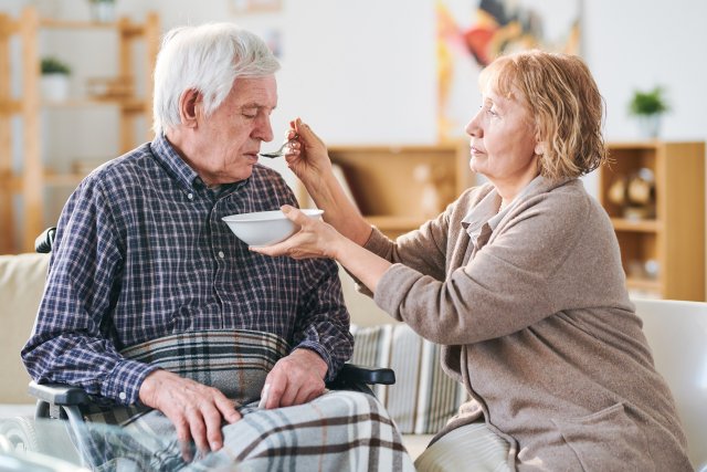 Mantelzorger helpt oudere man met eten