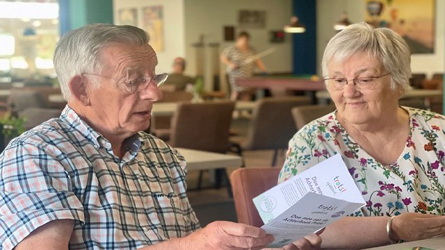 Ouderenadviseur helpt iemand met informatie in een folder