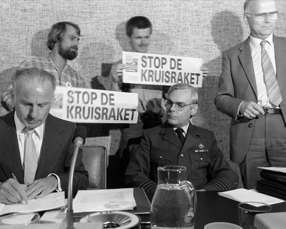 Burgemeester De Leeuw van Woensdrecht (links) tijdens de rumoerige raadsvergadering van 28 juni 1983. Naast hem kolonel Frans Schulte, commandant van Vliegbasis Woensdrecht. De voorgenomen plaatsing van kruisraketten daar zorgde voor het nodige protest. Copyright: Bas Steffen - Collectie West-Brabants Archief