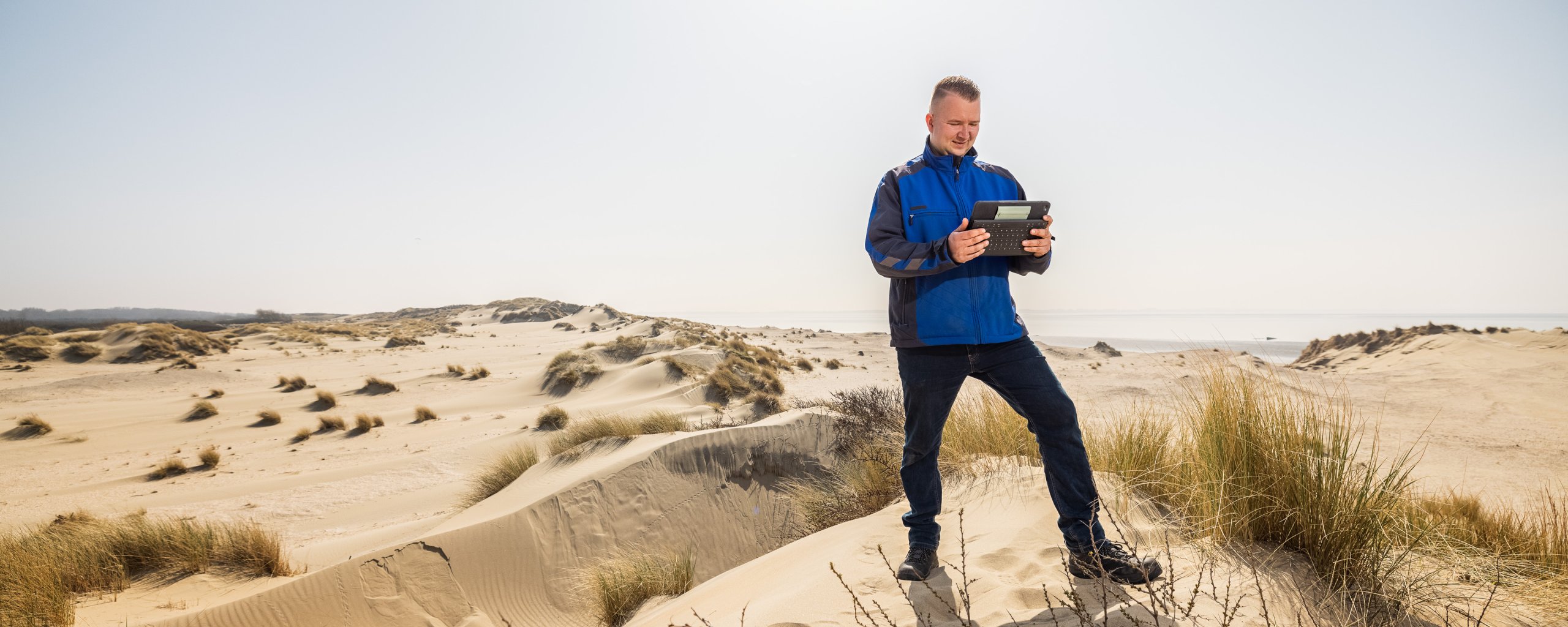 Medewerker van Hollandse Delta kijkt op een tablet. 