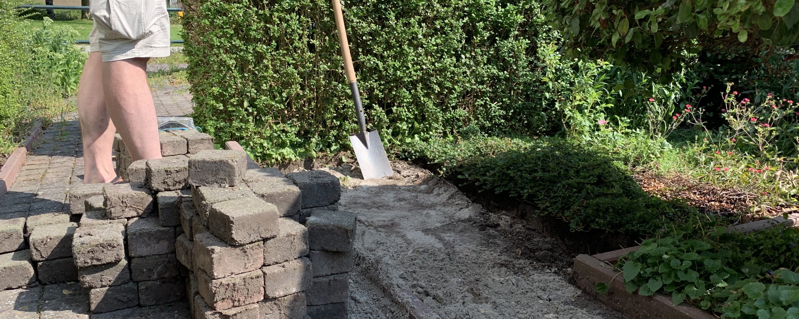 Een man haalt tegels uit de tuin en vervangt deze door groen als voorbeeld van waarvoor je de subsidie kunt gebruiken