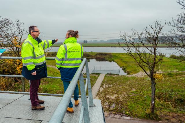 Twee waterschappers werken samen en overleggen bij de bezinkplas op het Eiland van Dordrecht