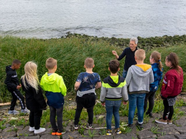 Leo geeft de kinderen uitleg op de dijk