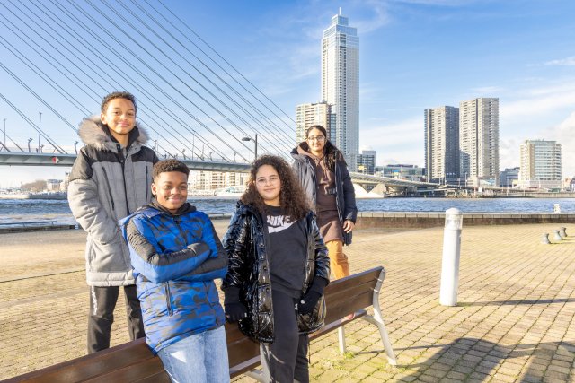 Vier kinderen van basisschool De Nieuwe Haven poseren op het Noordereiland voor de Erasmusbrug