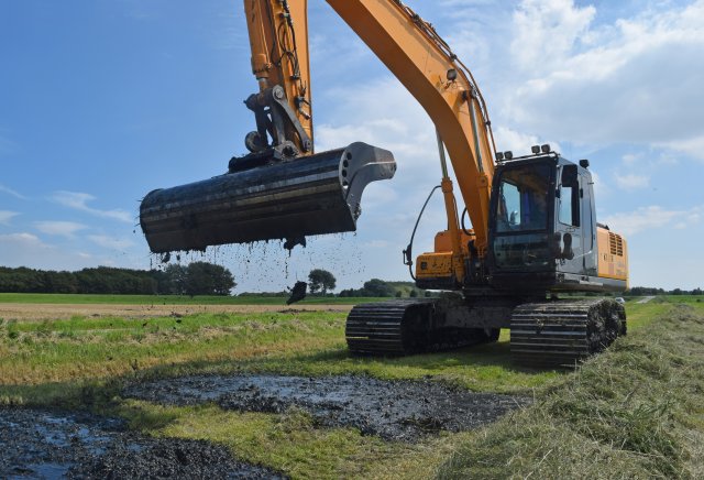 Een tractor legt bagger op de kant