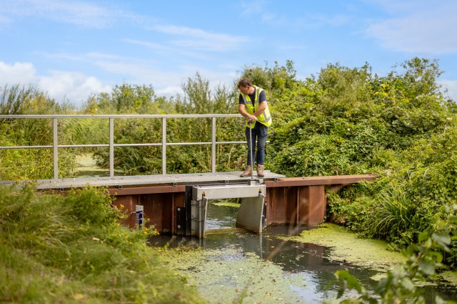 Een medewerker van het waterschap verlaagt het waterpeil.