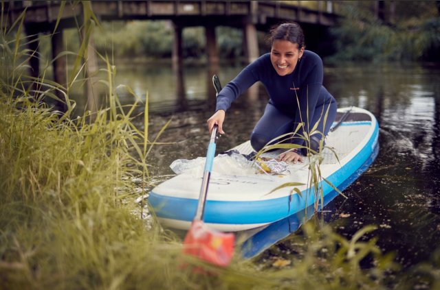 Vrouw op sup vist afval uit water