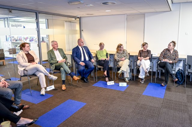 Minister Thierry Aartsen luistert geïnteresseerd naar de betrokkenen bij het OpGroeiPad