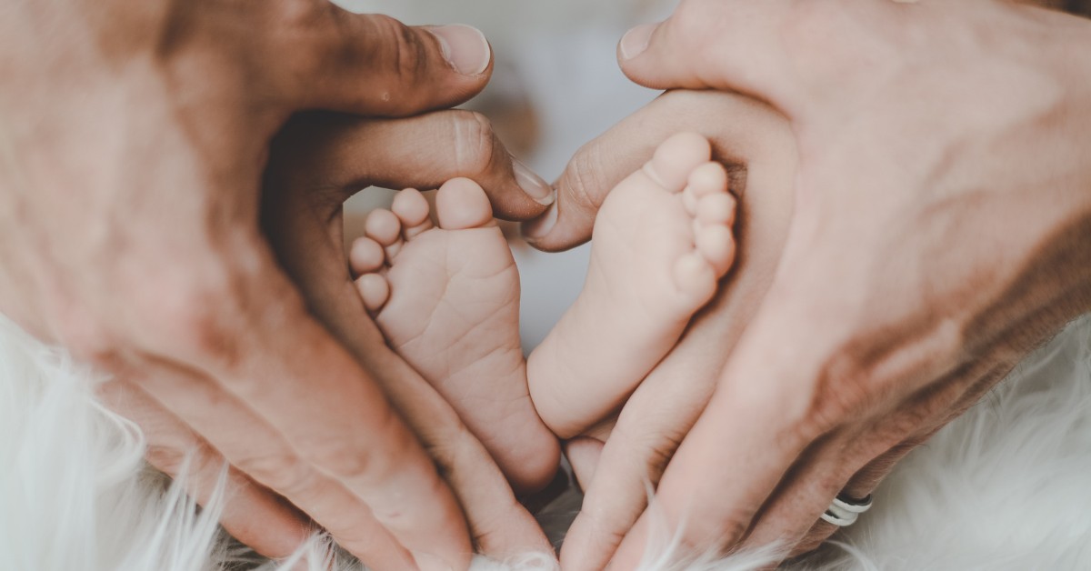 Babyvoetjes met de handen eromheen van 2 volwassenen