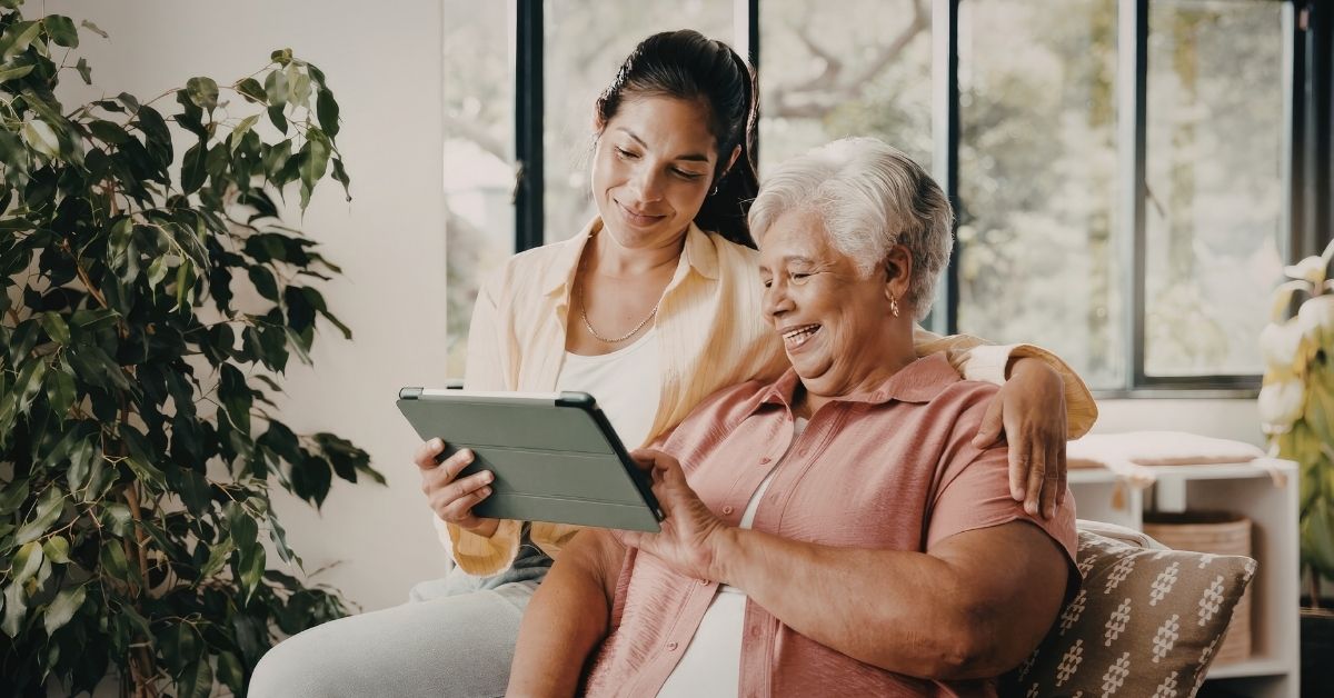 Een mantelzorger en een oudere vrouw achter een i-pad.