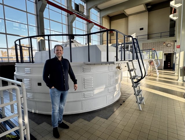 Man staat glimlachend in ruimte met ramen bij een wit gemaal