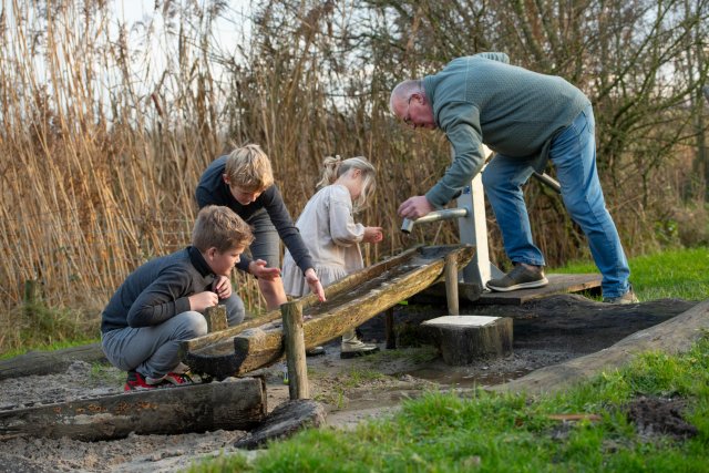 Kinderen en een opa die samen met een waterpomp spelen