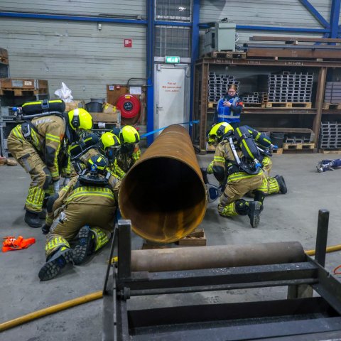 Deelnemers aan de oefening bezig met een persoon welke bekneld ligt onder een grote metalen buis