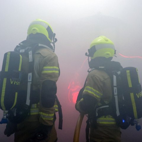 Twee brandweermensen in volle uitrusting in de rook