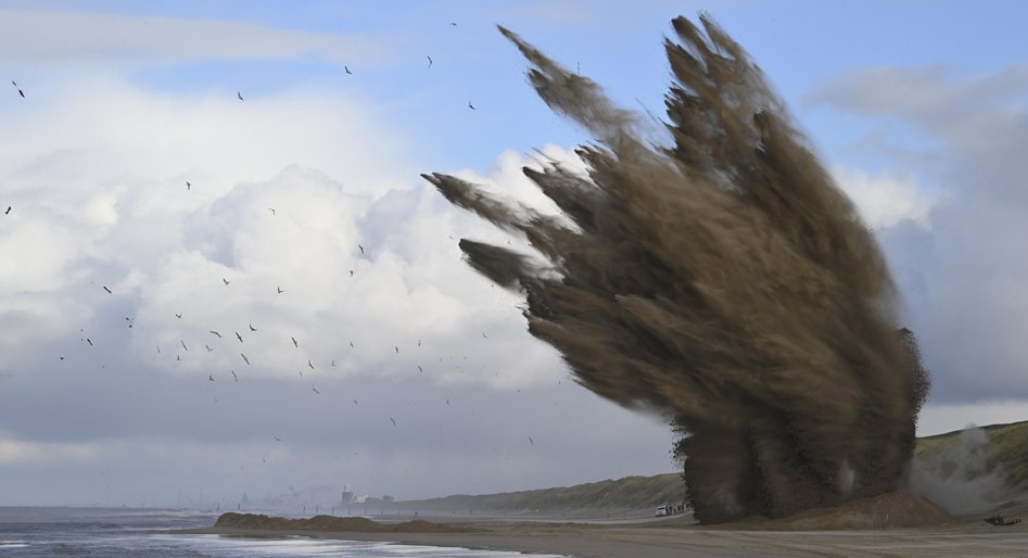 Meters zand worden de lucht in geslingerd als de bommen tot ontploffing gebracht worden op het strand