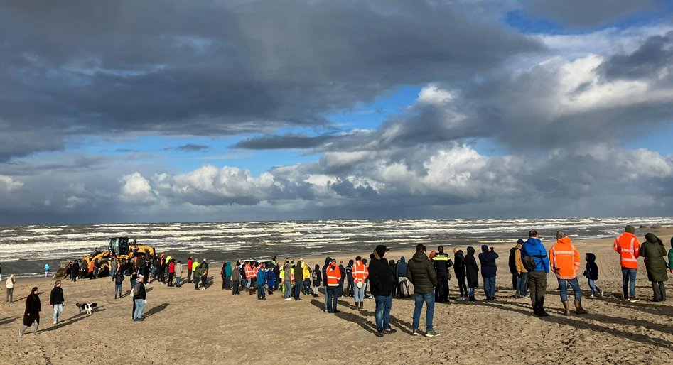 Veel mensen kijken naar de activiteiten rondom de bomruiming op het strand