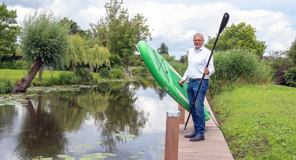 Wethouder Daan de Haas op een steiger aan de Ringvaart met in zijn hand een kano en peddel