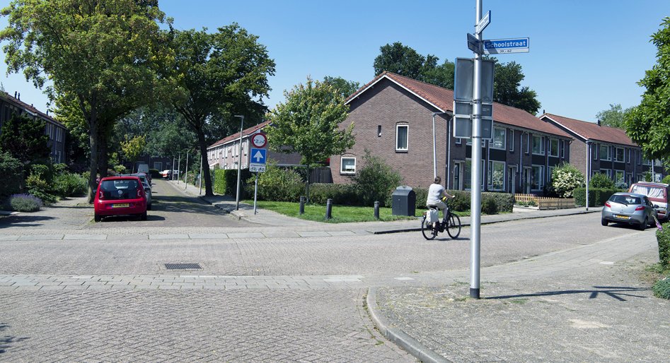 Huidige situatie Dorrestein-Noord, straat met geparkeerde auto's en een fietser
